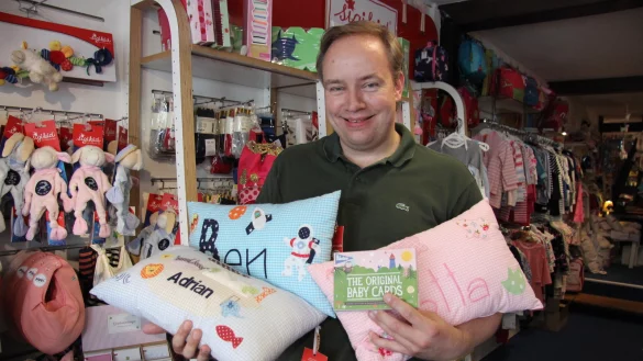 Stefan Heithecker pr&auml;sentiert verschiedene Kissen und die Baby-Cards. - &copy; Kirsten Fuhrmann