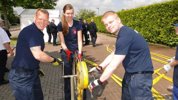 Mit vereinten Kr&auml;ften wickelt das Horn-Bad Meinberger Trio den Schlauch auf, der zuvor zum L&ouml;schangriff eingesetzt wurde: (von links) Hauptfeuerwehrmann Maik Kalous, Unterbrandmeisterin Rebecca Hennemann und Unterbrandmeister Nils Hammelmann. - &copy; Hajo G&auml;rtner