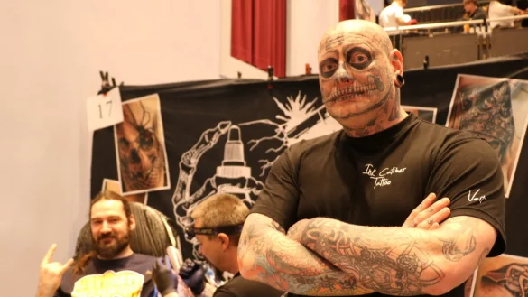 Veit Anders (von rechts) hat schon diverse T&auml;towierungen im Gesicht und an den Armen. Er steht am Messestand, w&auml;hrend sein Kollege Benny Busch Kunde Johann Braun ein Tattoo sticht. - &copy; Till Sadlowski